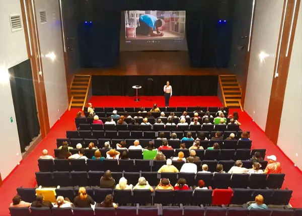 Función en curso en el Teatro Ribas con público completo y proyección en pantalla principal